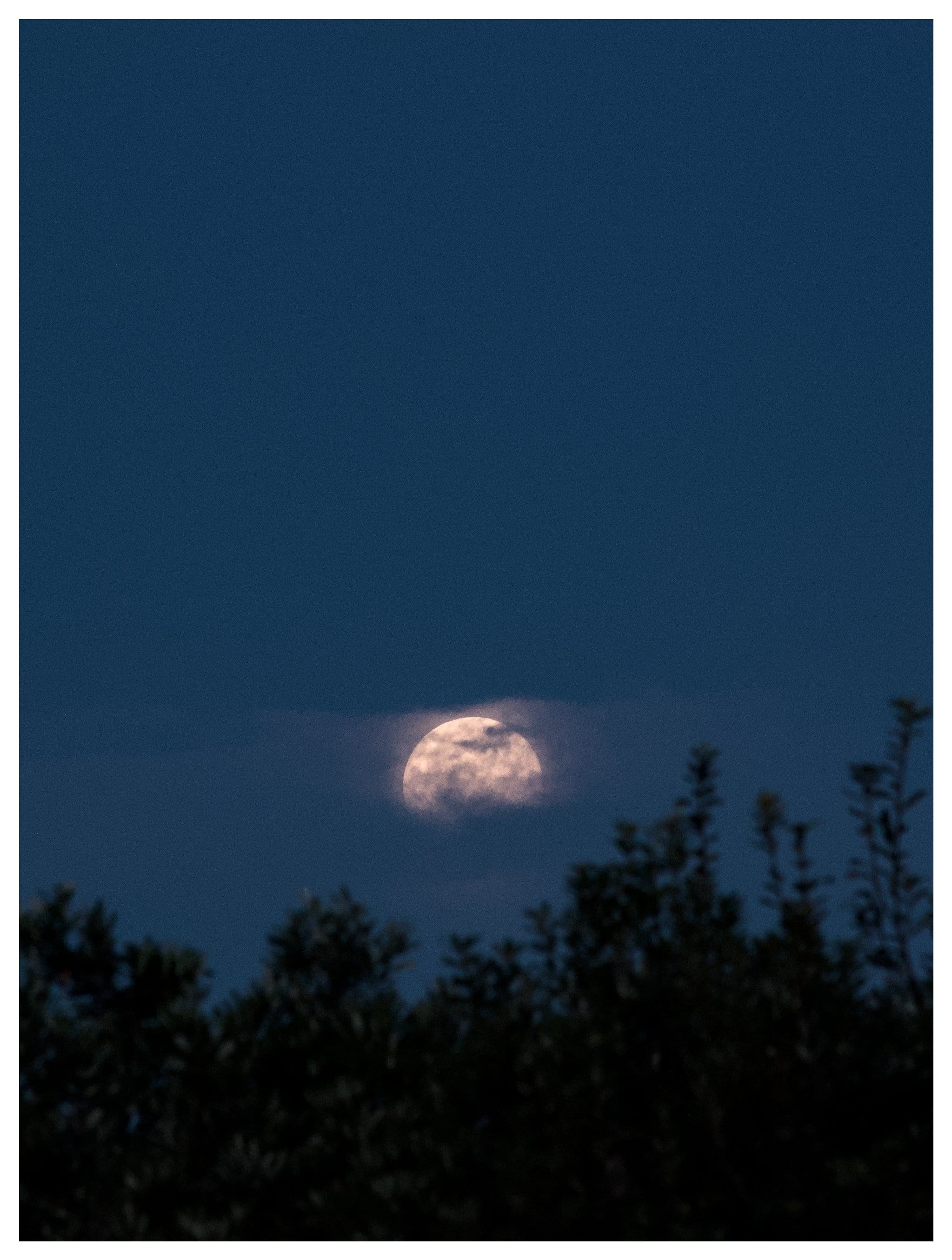 Moon rising behind the clouds over Old Bar Beach
